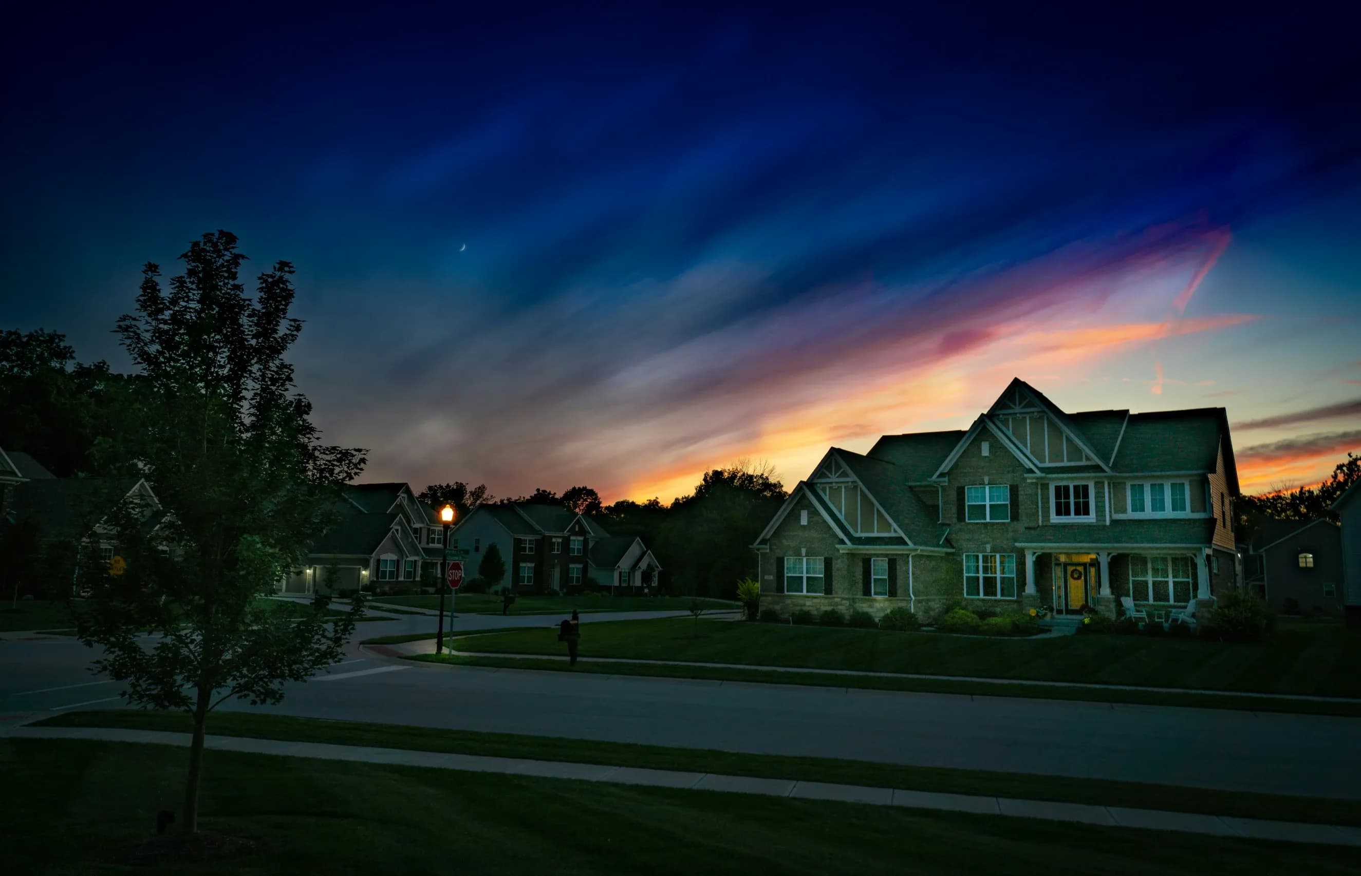 A house in a residential neighborhood with a sunset in the background.