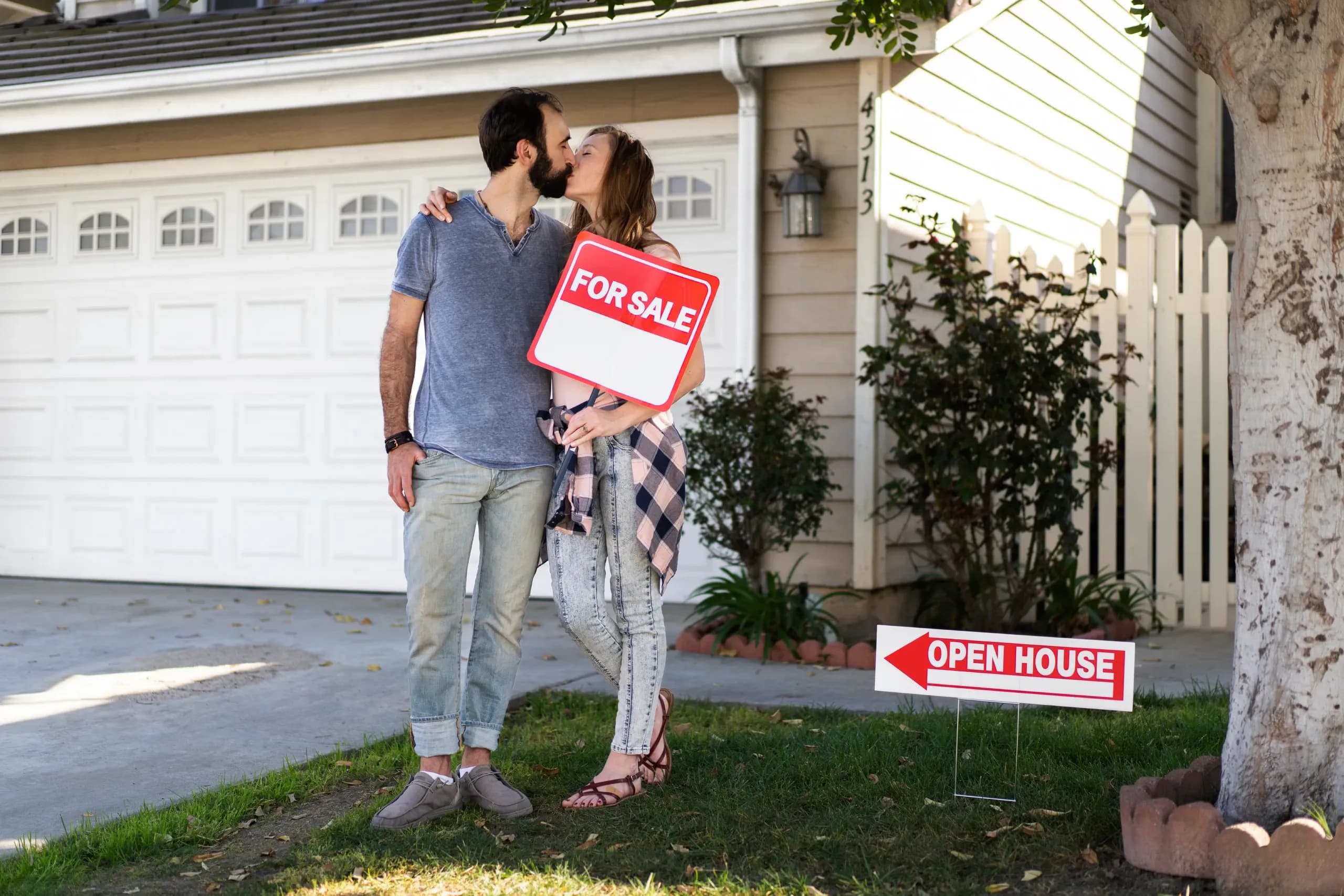 a couple kissing in front of a house they just bought